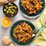 Flavorful Sicilian Cauliflower Salad (vegan) with oranges, green olives, raisins and capers on green glazed plates with crusty bread BoulderLocavore.com