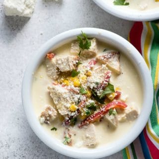 White bowl of Jalapeno Corn Chicken Chowder soup with cojito cheese and chopped cilantro