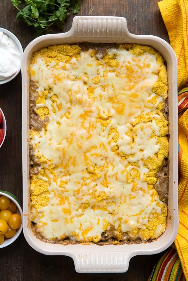 Black Bean Pumpkin Tamale Pie with melted cheese in an enamel French baking pan 