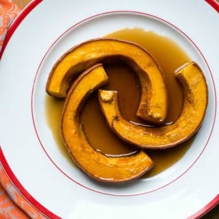 Three sliced of Caramelized Roasted Pumpkin in a caramel cinnamon ginger sauce in an oversized white bowl with red trim