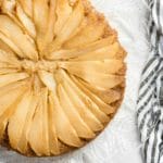 Caramelized Pear Upide Down Cake on a glass etched platter with black and white striped cloth napkin on a gray painted surface BoulderLocavore.com