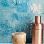 Colorado Bulldog cocktail with copper cocktail shaker and blue distressed plaster wall