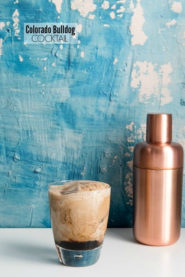 Colorado Bulldog cocktail with copper cocktail shaker and blue distressed plaster wall