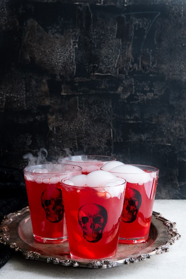 Smoking, blood red Slow Cooker Vampire Punch in skull glasses on an antique silver tray 