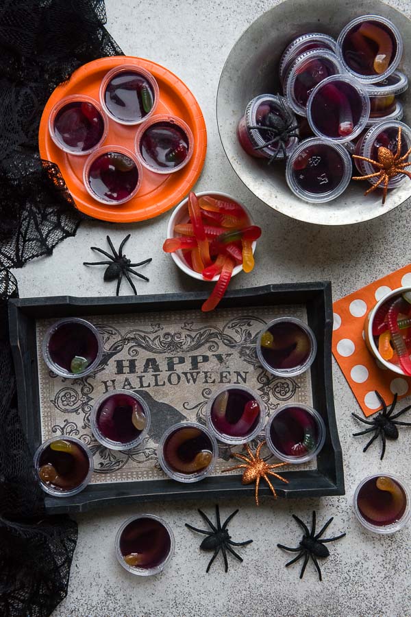 Spooky Halloween Squirm Jello shots with gummy worms inside on a Halloween serving tray, with spiders 