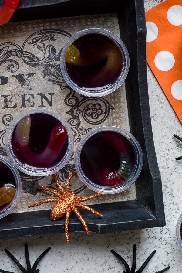 Halloween grape Squirm Jello Shots with gummy worms in small snack containers with spiders