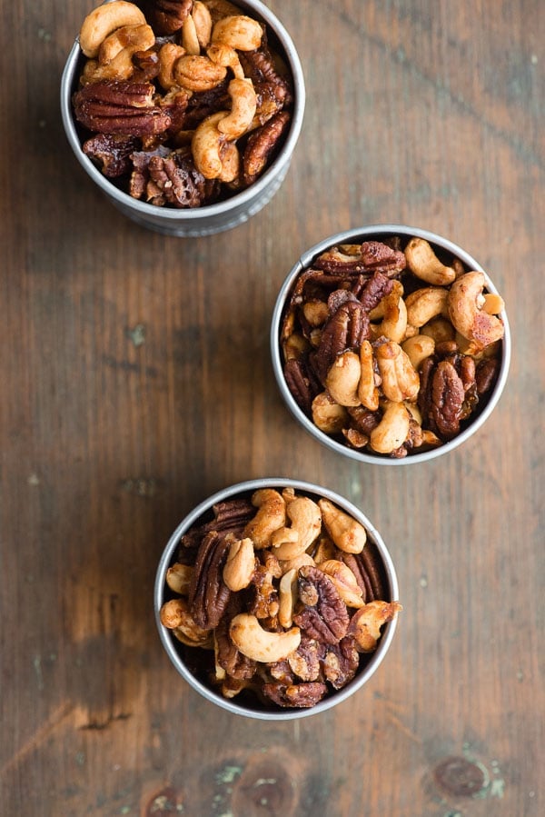 Top view of three galvanized cans of Sweet Spiced Nuts, cashews and pecans in a candied glaze 