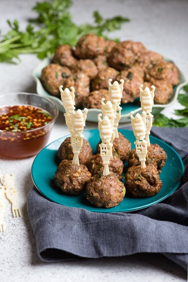 Thai Chicken Meatballs on a teal appetizer plate with vintage Buddha cocktail skewers and dipping sauce 