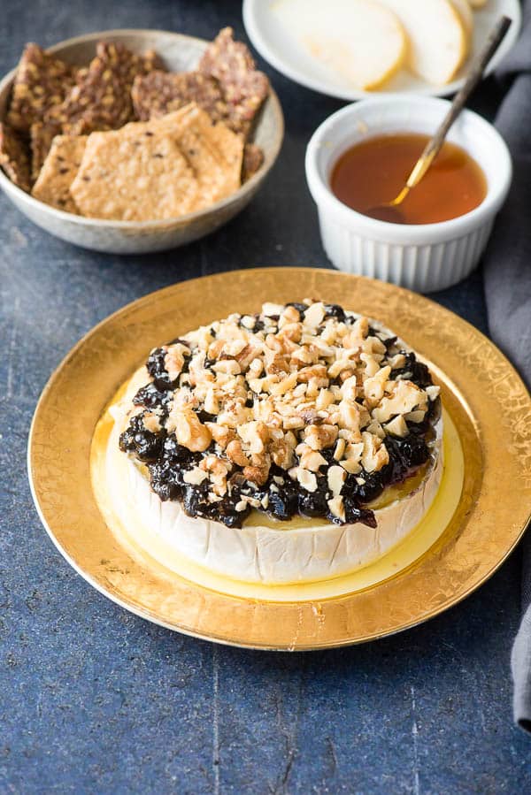 Blueberry Walnut Baked Brie drizzled with honey on an antique gold-rimmed plate 