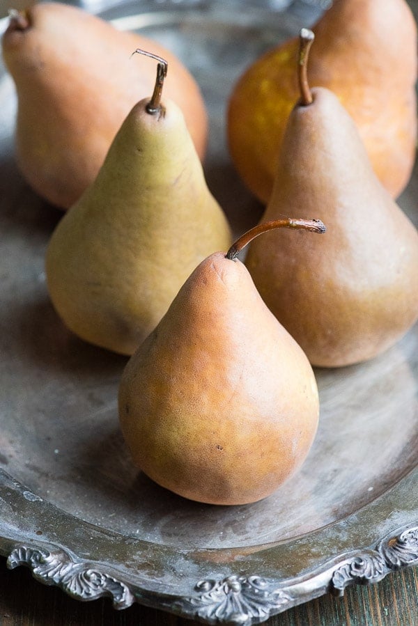 Five Bosc pears on an antique silver platter