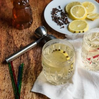 Glasgow Hot Toddy with clove-studded lemon slice in Waterford crystal etched glasses with a handled jigger