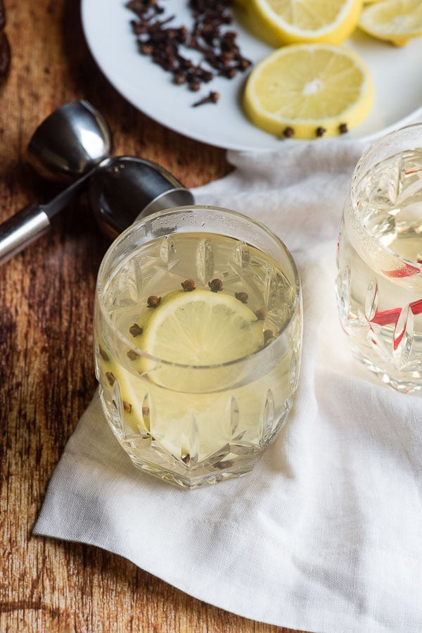 Glasgow Hot Toddy in a cut crystal glass with clove-studded lemon slice and jigger