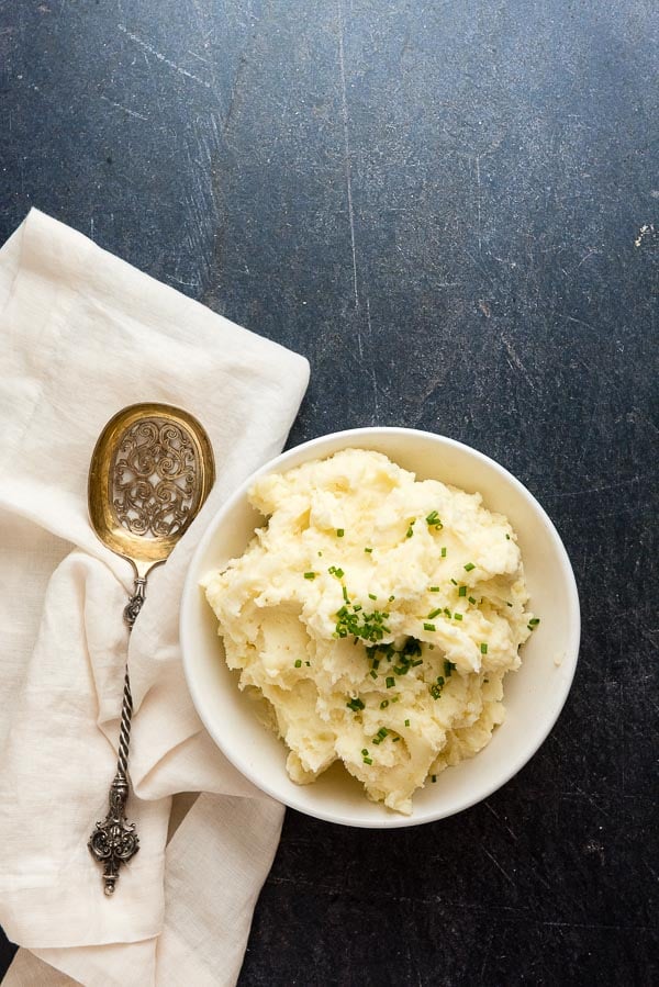 Instant Pot mashed potatoes in a white bowl with antique French serving spoon and cream linen napkin 