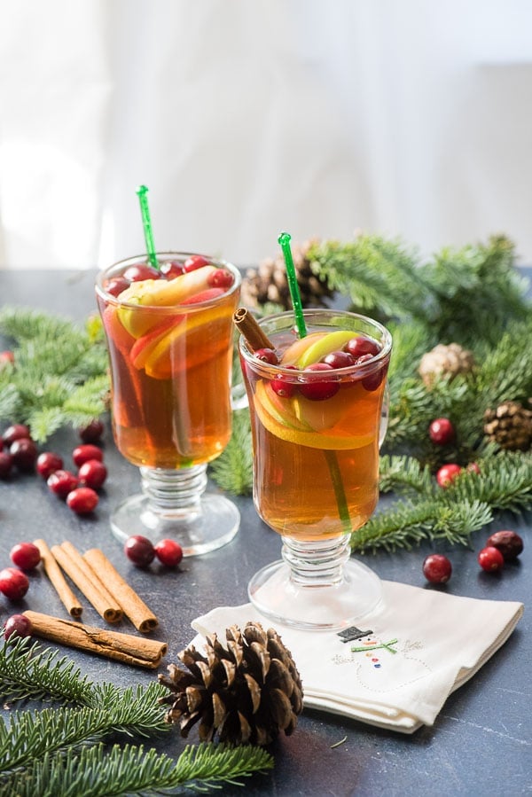 Cranberry Apple Hot Toddy cocktails in glass mugs with pin branches and cranberries