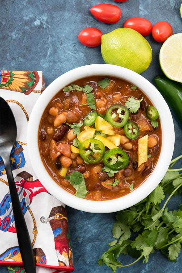 Single serving of Vegan Instant Pot Recipe: 4 Bean Chili with sliced jalapenos, yellow bell pepper and torn cilantro leaves in a white bowl