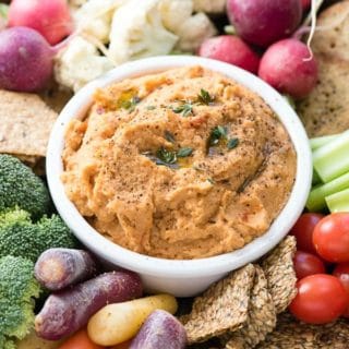 5-Minute Smoked Paprika Garlic Bean Dip in a white bowl with cut vegetables and crackers