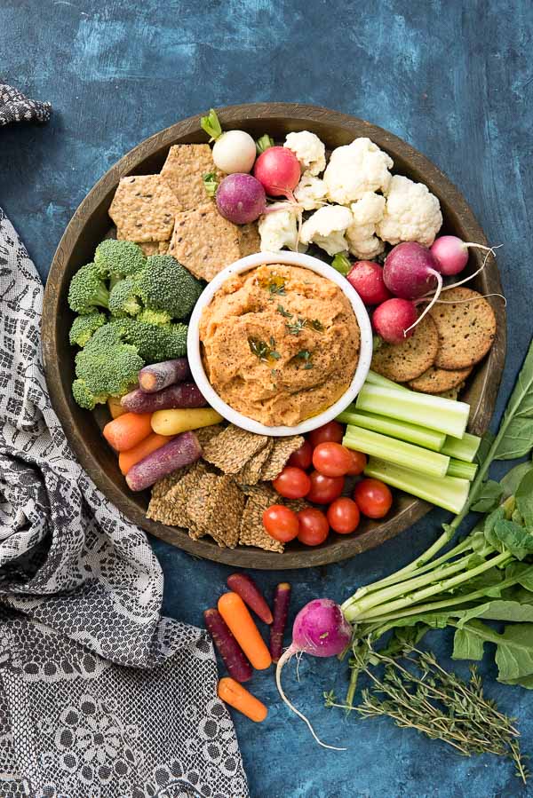 5-Minute Smoked Paprika Garlic Bean Dip with fresh vegetables and gluten-free cracker s on a bronze tray