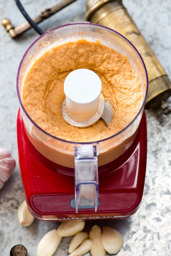 5-Minute Smoked Paprika Garlic Bean Dip in a mini chopper with garlic cloves, and peppermill