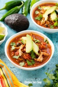 Instant Pot Chicken Taco Soup in white bowls with avocado slices, torn cilantro leaves, jalapeno pepper