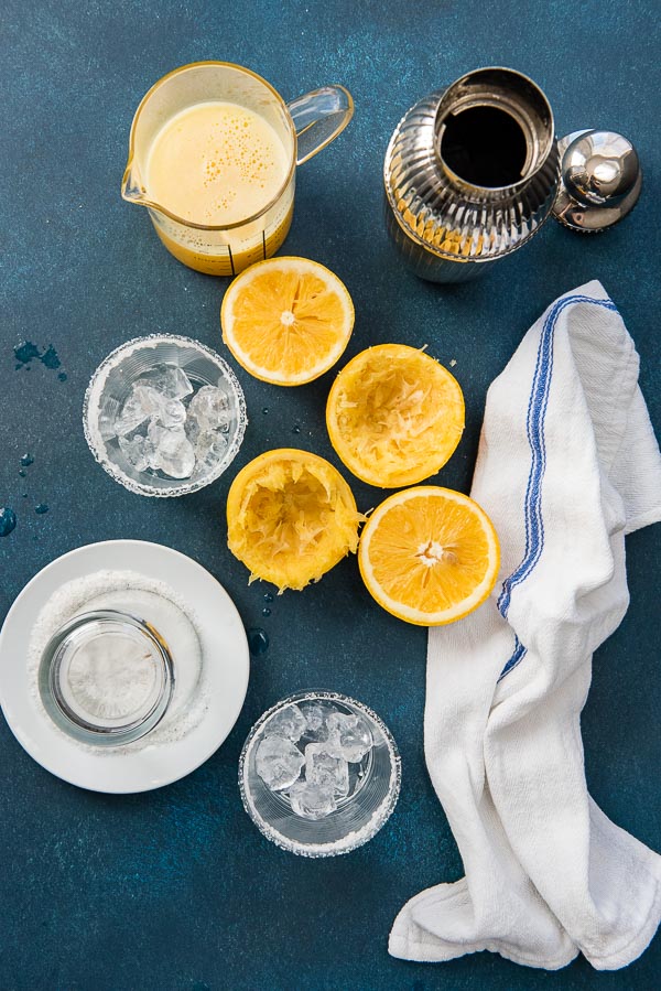 Fresh grapefruit juice, halved grapefruits, salt-rimmed glasses and cocktail shaker for Salty Dog cocktail