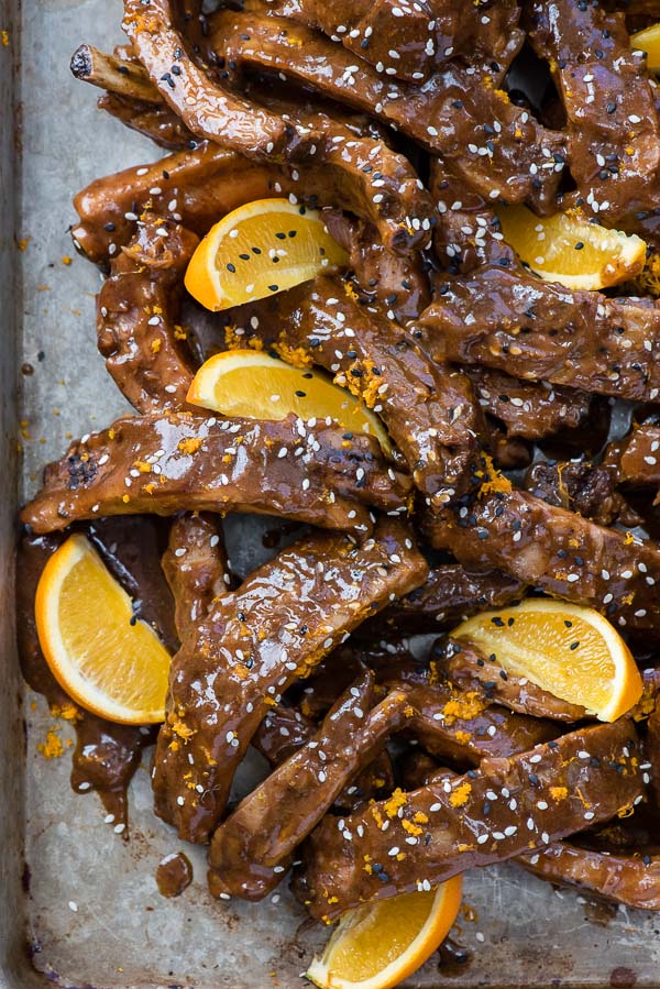 Slow Cooker Sweet Sesame Baby Back Ribs with glaze and orange wedges on a metal baking sheet