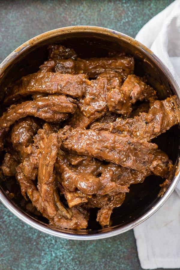 Slow Cooker Sweet Sesame Baby Back Ribs tossed with glaze in a metal bowl