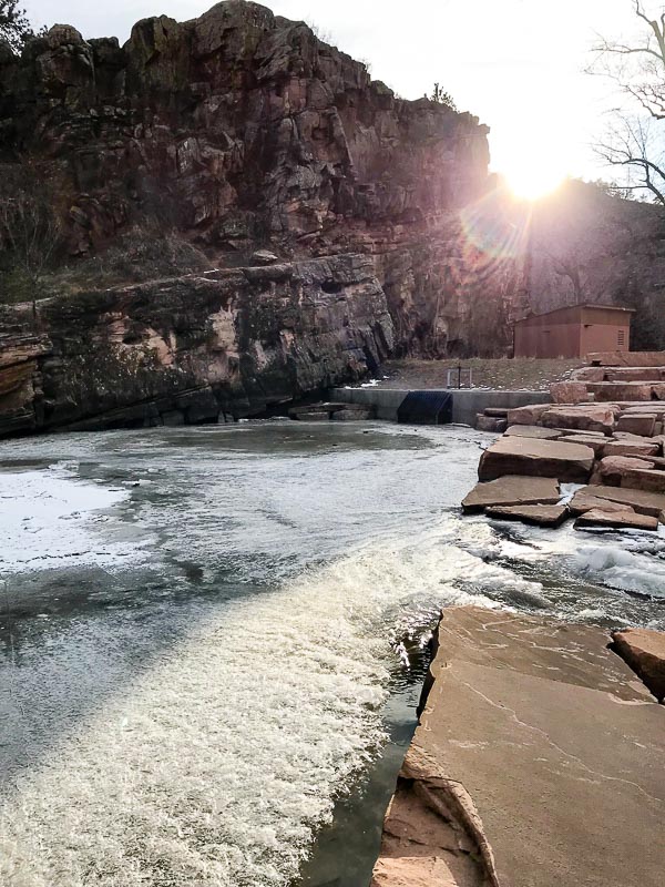 Parially frozen rive with sun setting over cliffs in the background