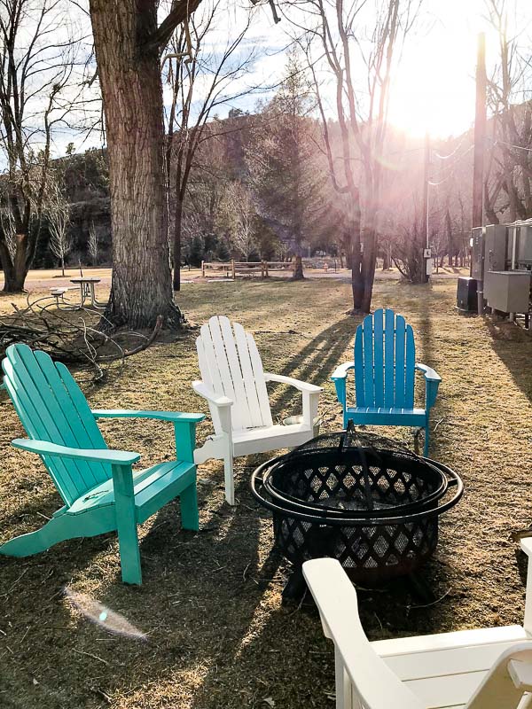 Firepit at WeeCasa Resort with colorful adirondack chairs and a wroght iron fire basket