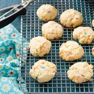 Freshly baked gluten-free Cake Mix Funfetti Cookies on a cooling rack with cookie scoop and flowered cloth