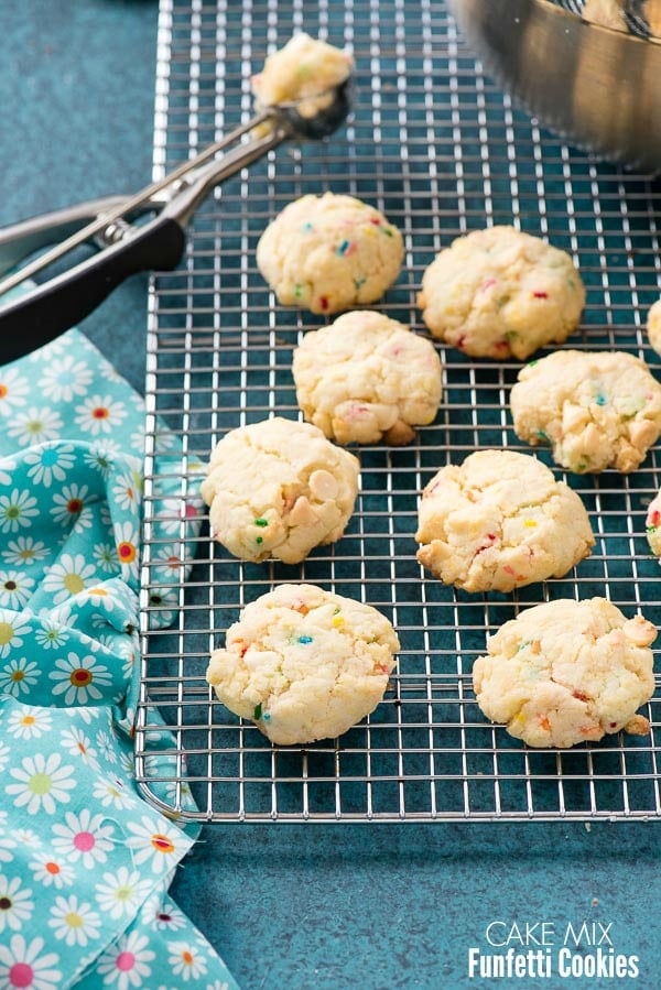 Freshly baked gluten-free Cake Mix Funfetti Cookies on a cooling rack with cookie scoop and flowered cloth