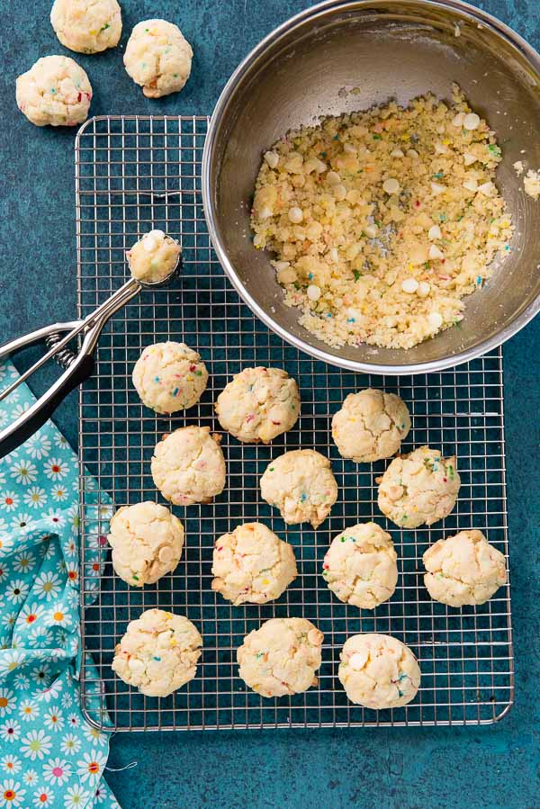 Cake Mix Funfetti Cookies on cooling rack with mixing bowl of dough and cookie scoop