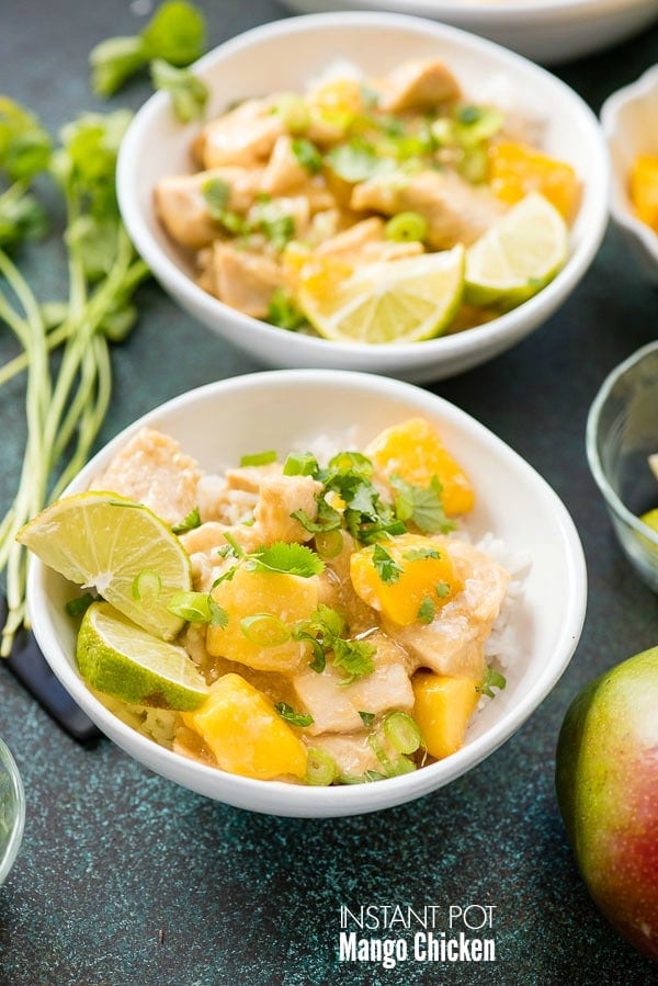 Instant Pot Mango Chicken with cilantro, scallions and lime wedges on rice