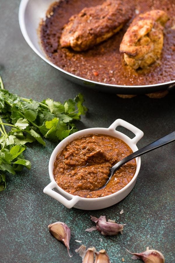 Mole sauce in a white ramekin with black spoon for mole-roasted chicken with fresh cilantro