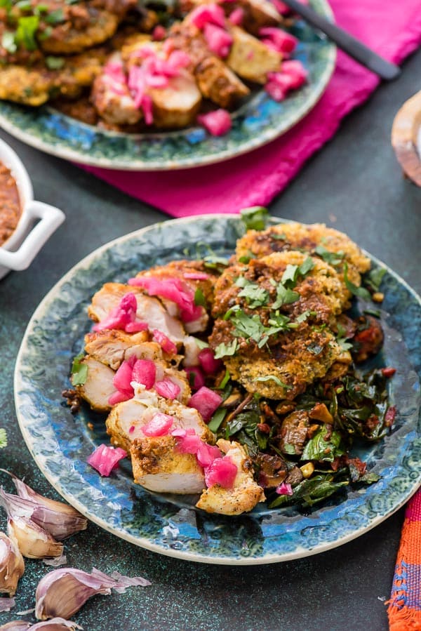 Mole-Roasted Chicken with arepas, sauteed vegetables on a green rimmed plate