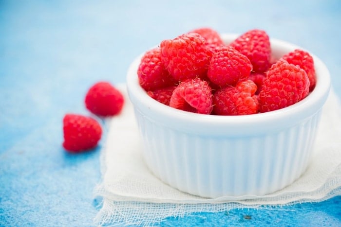 White bowl of raspberries