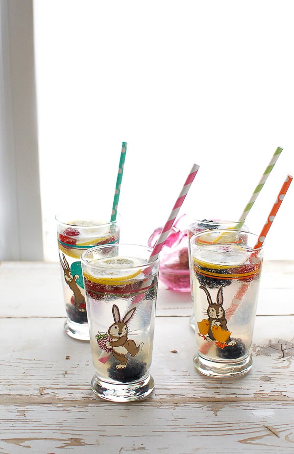 Four Easter-themed highball glasses of Elderflower Gin Fizz cocktails with colorful straws