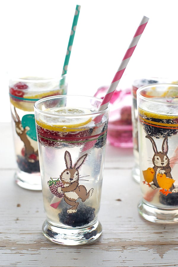 Easter tall glasses with Elderflower Gin Fizz cocktails with lemon slices, colorful straws and frozen berries