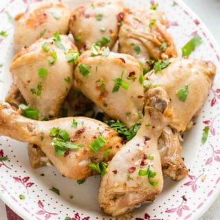 A vintage platter of Instant Pot Ginger Soy Chicken Drumsticks with cilantro, green onion and red pepper flakes garnish