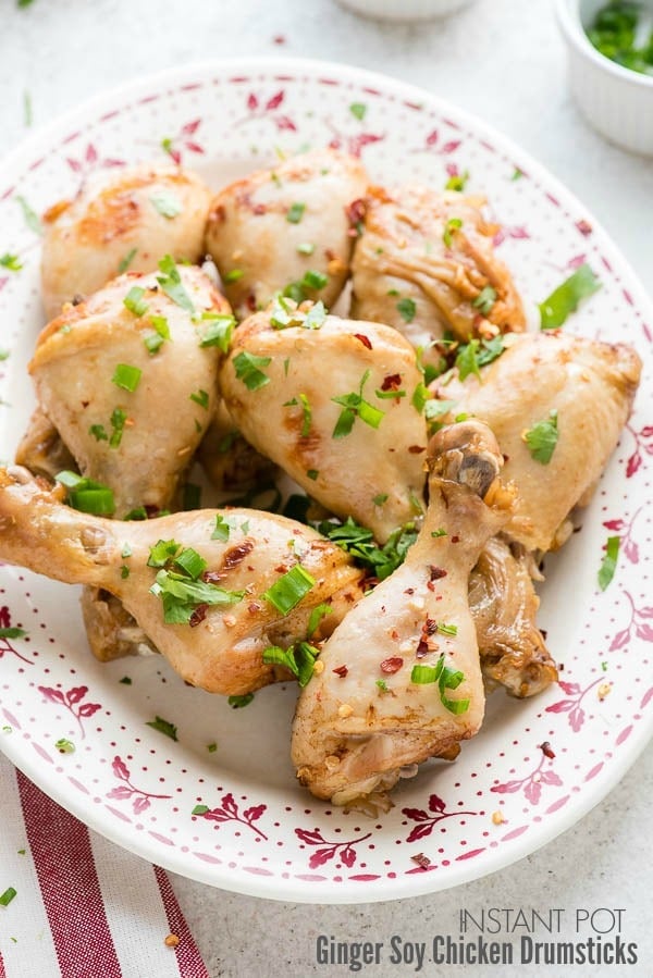 A vintage platter of Instant Pot Ginger Soy Chicken Drumsticks with cilantro, green onion and red pepper flakes garnish
