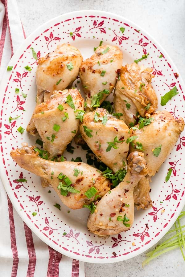 Floral platter of Instant Pot Ginger Soy Chicken Drumsticks topped with green onion, cilantro and red pepper flakes