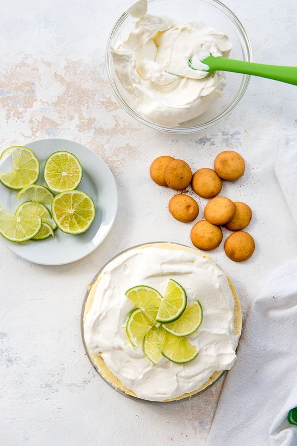 Instant Pot Lime Cheesecake with lime slices, vanilla wafers and whipped cream in a clear bowl