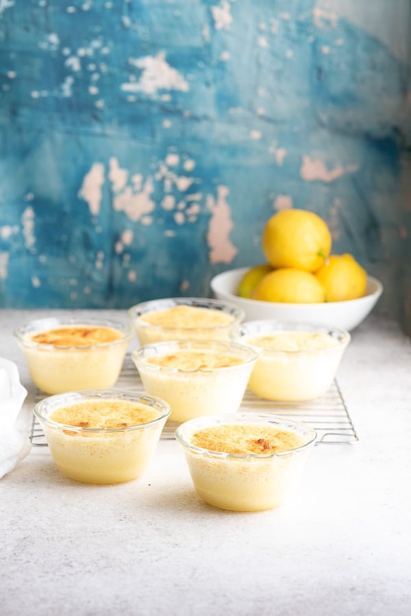 Glass custard cups of lemon baked custard and a bowl of lemons