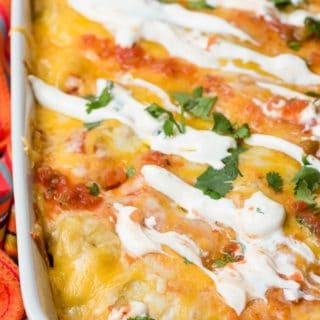 White baking dish of Christmas Breakfast Enchilada Casserole with melted cheese and sour cream on top