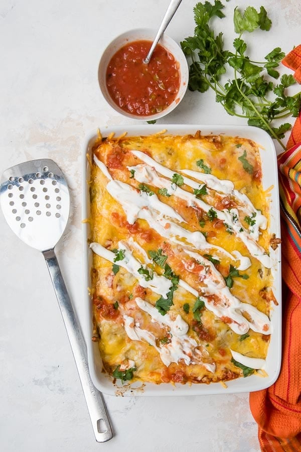 Baked Christmas Breakfast Enchilada Casserole with melted cheese, sour cream, salsa and cilantro on top