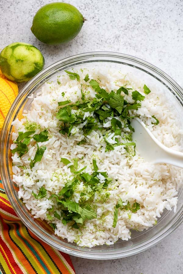 Freshly cooking Instant Pot long grain white rice with chopped fresh cilantro and lime zest in a glass bowl