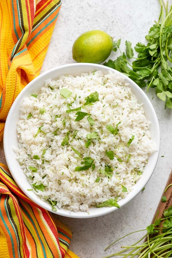 Instant Pot Cilantro Lime Rice with fresh cilantro sprigs, limes and Mexican kitchen towel