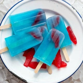 Blue Lagoon Cocktail popsicles on a white plate on ice