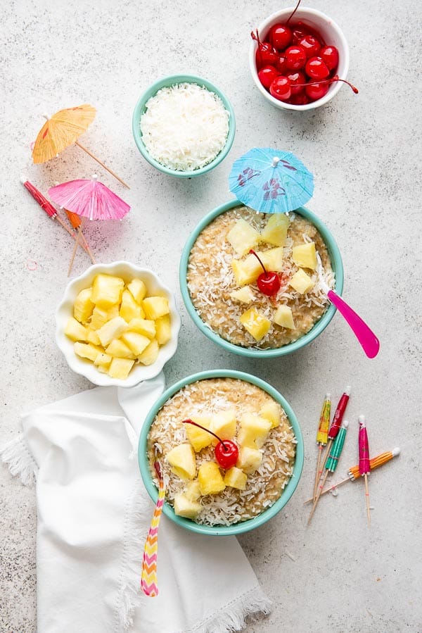 Bowls of Instnat Pot Pina Colada Steel Cut oats with paper cocktial umbrellas, grated coconut and pineapple chunks