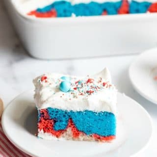 A slice of Red White and Blue Cake with whipped cream and sprinkles