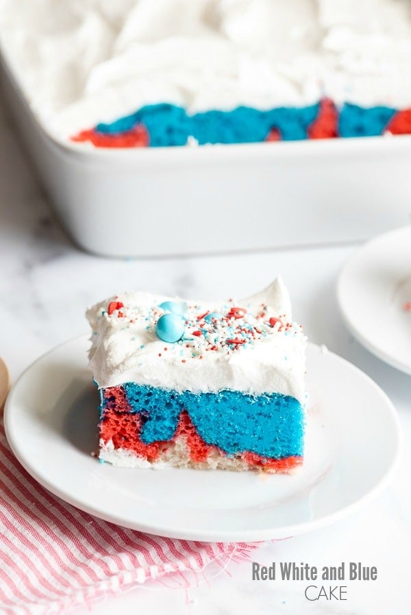 A slice of Red White and Blue Cake with whipped cream and sprinkles